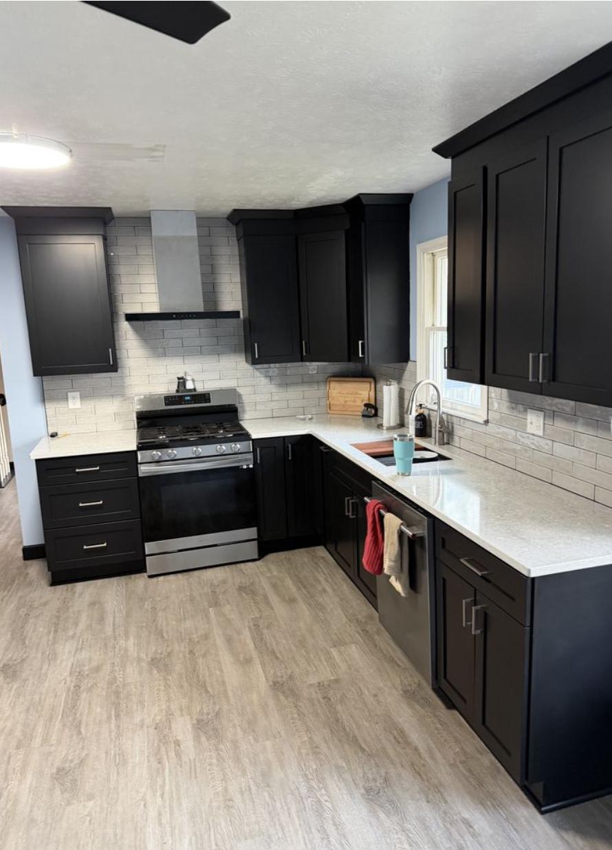 Kitchen with cabinets painted matte black and a subway tile backsplash