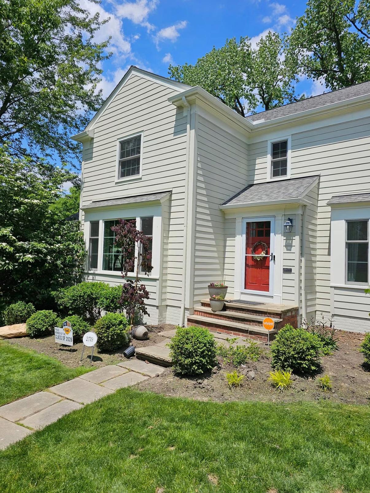 Two-story home freshly painted cream with a bold red front door