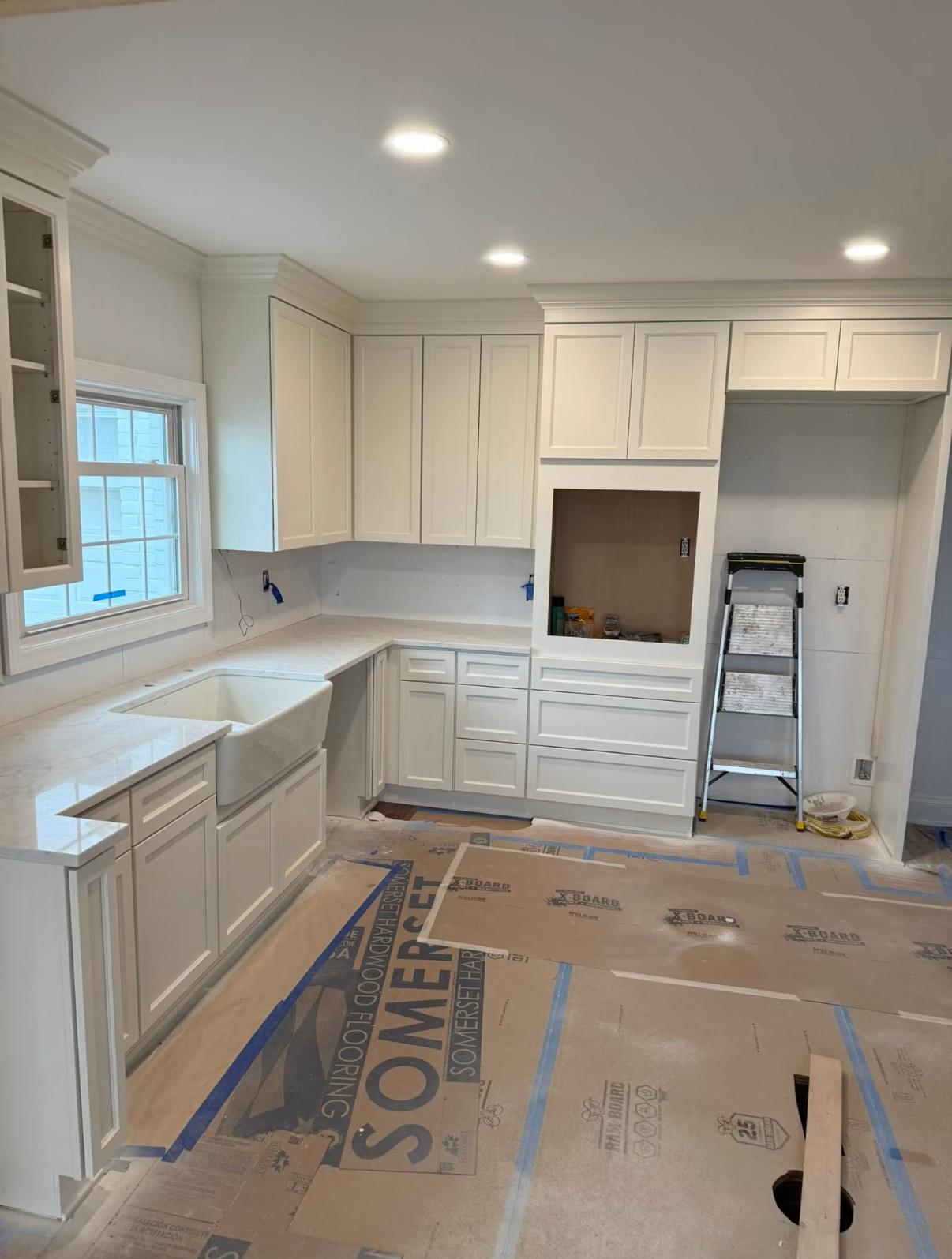 White kitchen cabinets under construction with a farmhouse sink